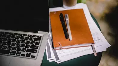 Planner and pens on table with laptop